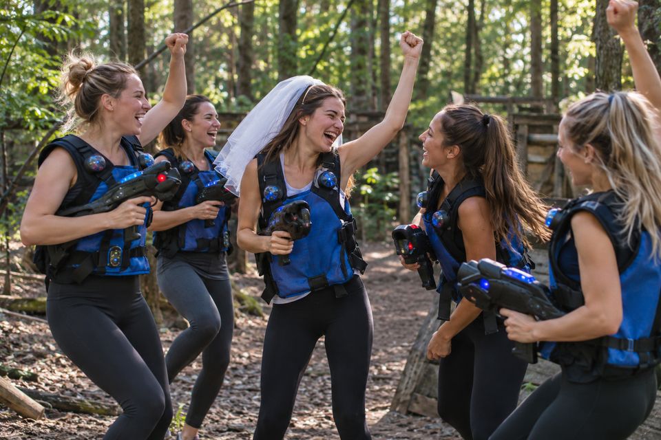 Groep vrouwen in blauwe vesten viert een vrijgezellenfeest in het bos